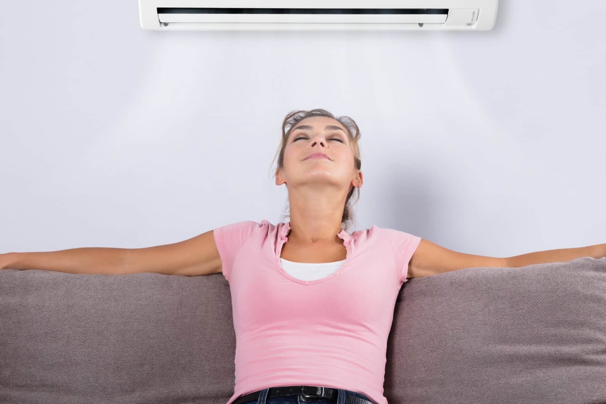 Indoor Air Quality, A woman Relaxing Under The Air Conditioner.