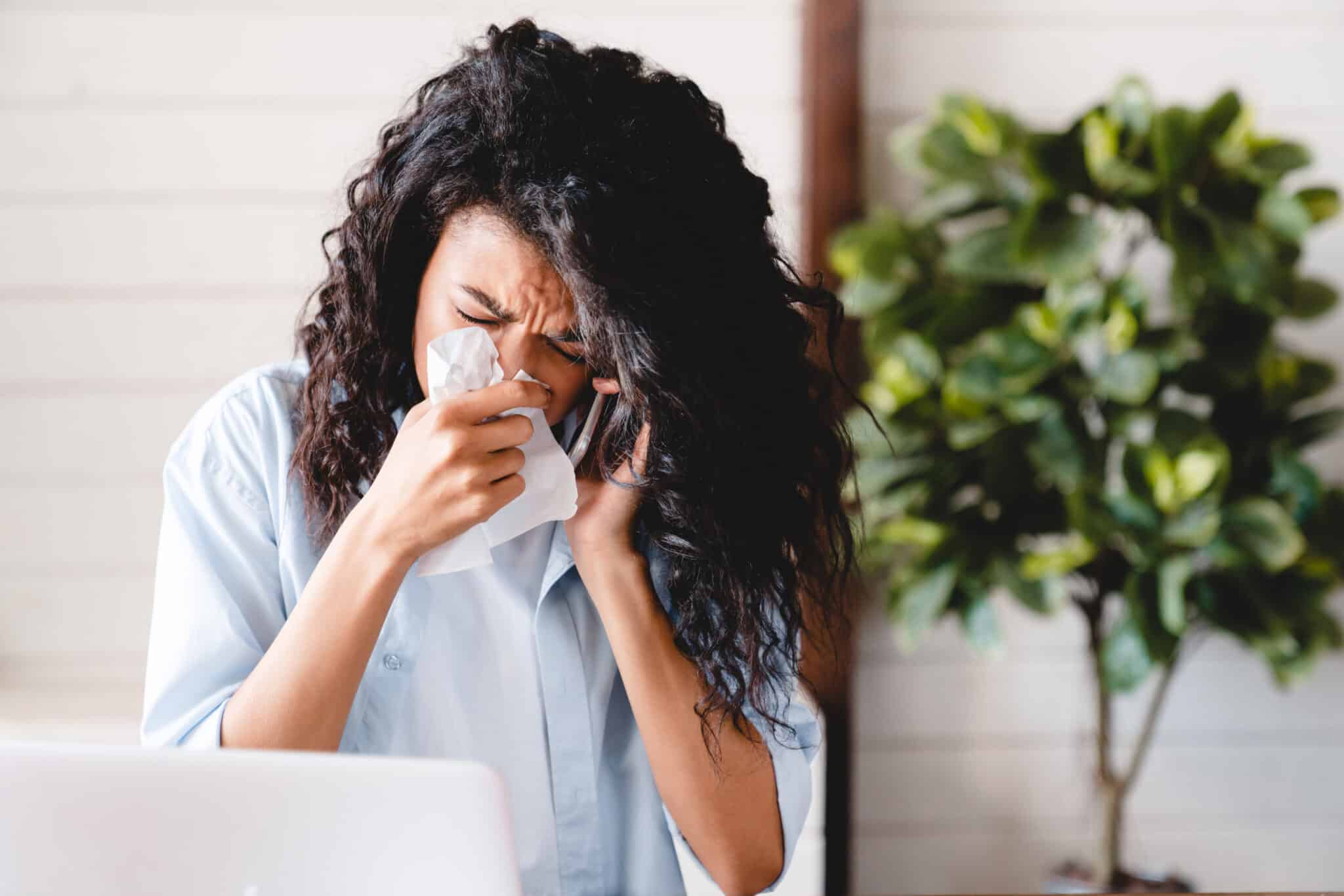 A woman with a cold, sitting at a desk with a laptop and sneezing due to allergies, Furnace short cycling