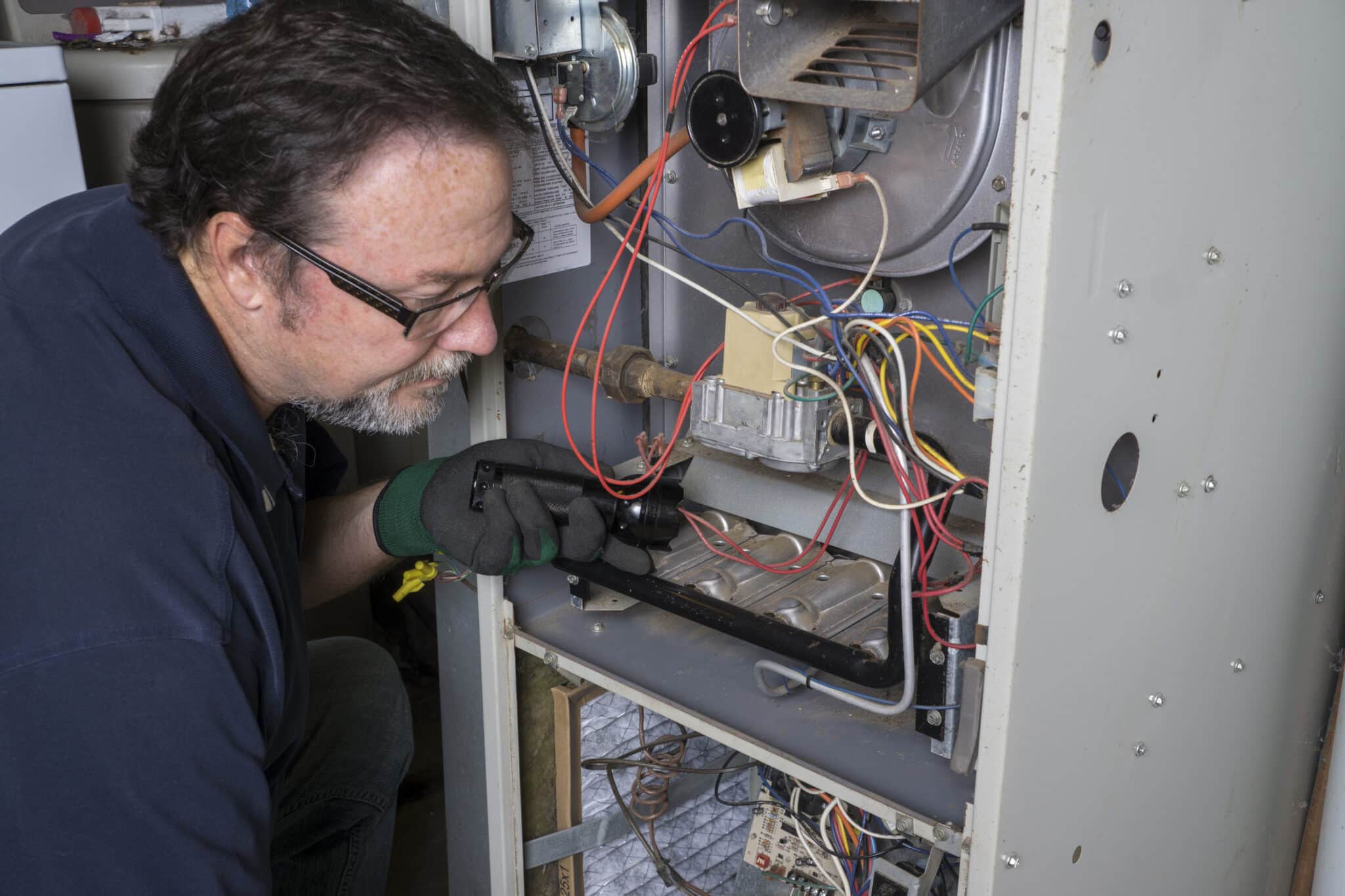 Technician Looking Over A Gas Furnace, Heating Repair.