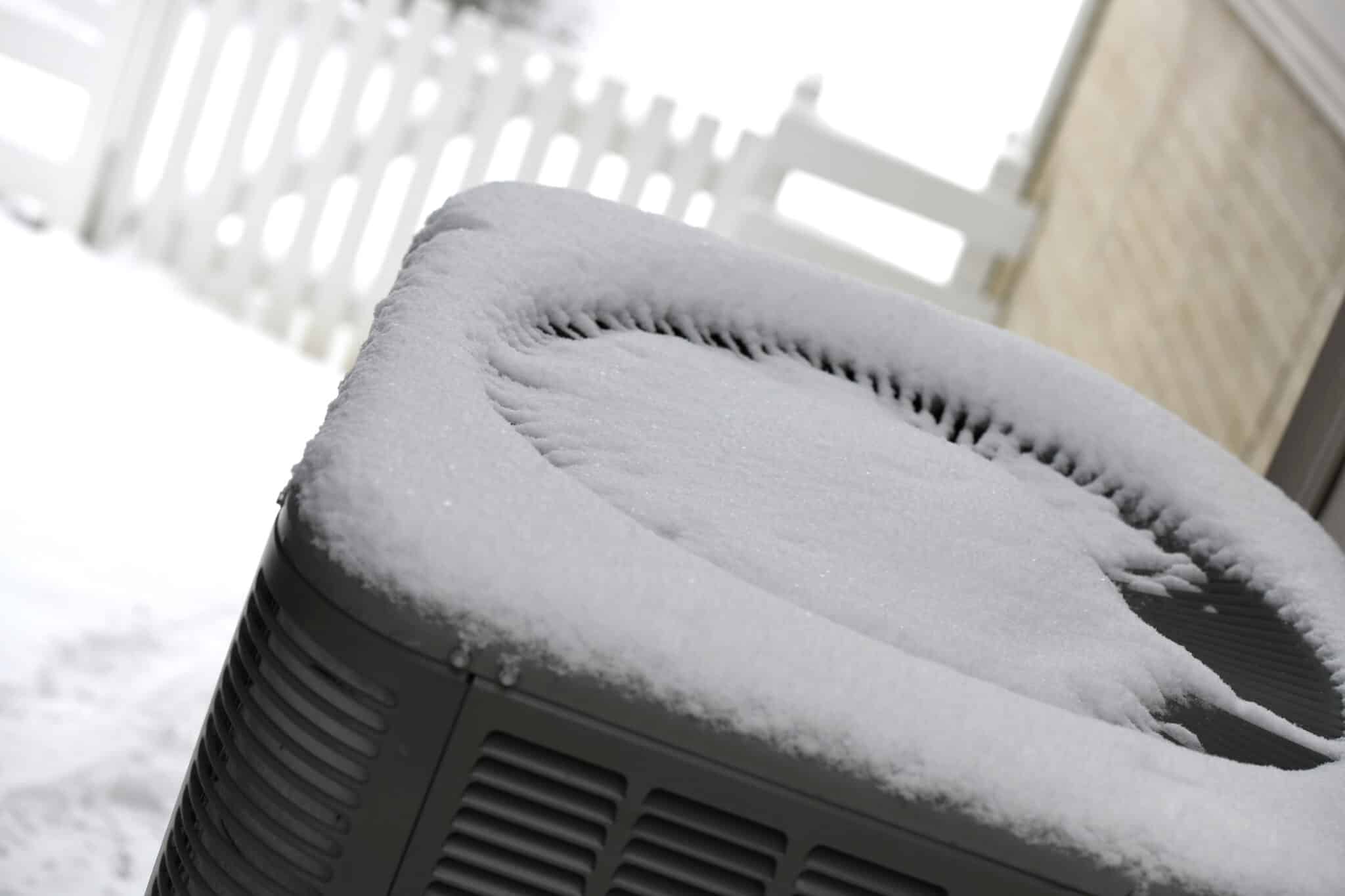 Fresh snow on top of a heat pump, HVAC tips for winter maintenance.